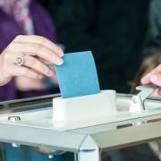 Main présentant un bulletin de vote à une urne