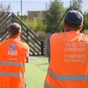 Agents de la Ville de Chartres et de Chartres métropole de dos, avec des gilets oranges