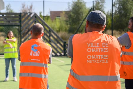 Agents de la Ville de Chartres et de Chartres métropole de dos, avec des gilets oranges