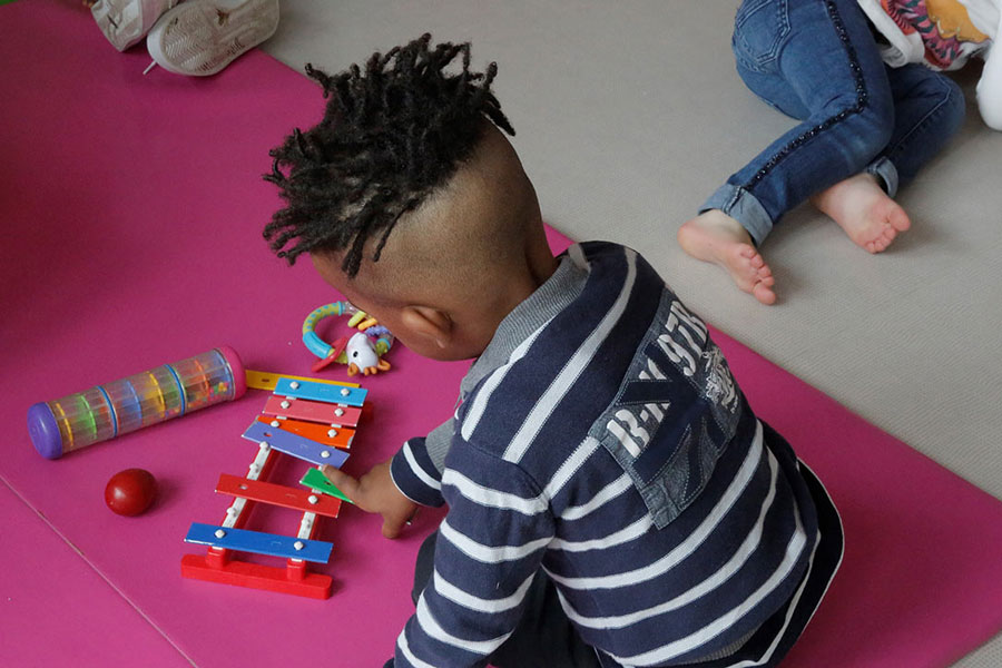 Un jeune enfant qui joue avec un xylophone en bois dans un établissement petite enfance