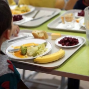 Des enfants qui mangent à la cantine, avec des plateaux garnis de nourritures