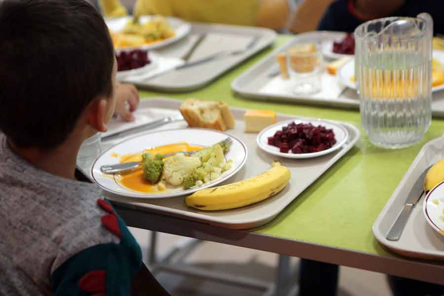 Des enfants qui mangent à la cantine, avec des plateaux garnis de nourritures
